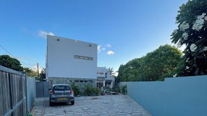 Ein gepflasterter Weg führt zu einem modernen Gebäude, auf dem ein Auto geparkt ist.