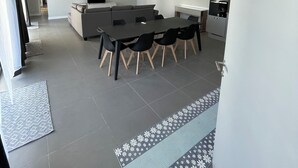 Ein modernes Wohnzimmer mit Essbereich, Küche und einem großen Fenster.