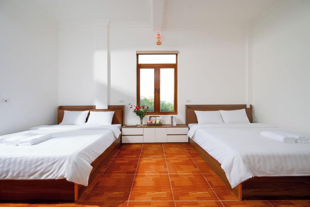 A hotel room with two single beds, a window with a view, and a tiled floor.