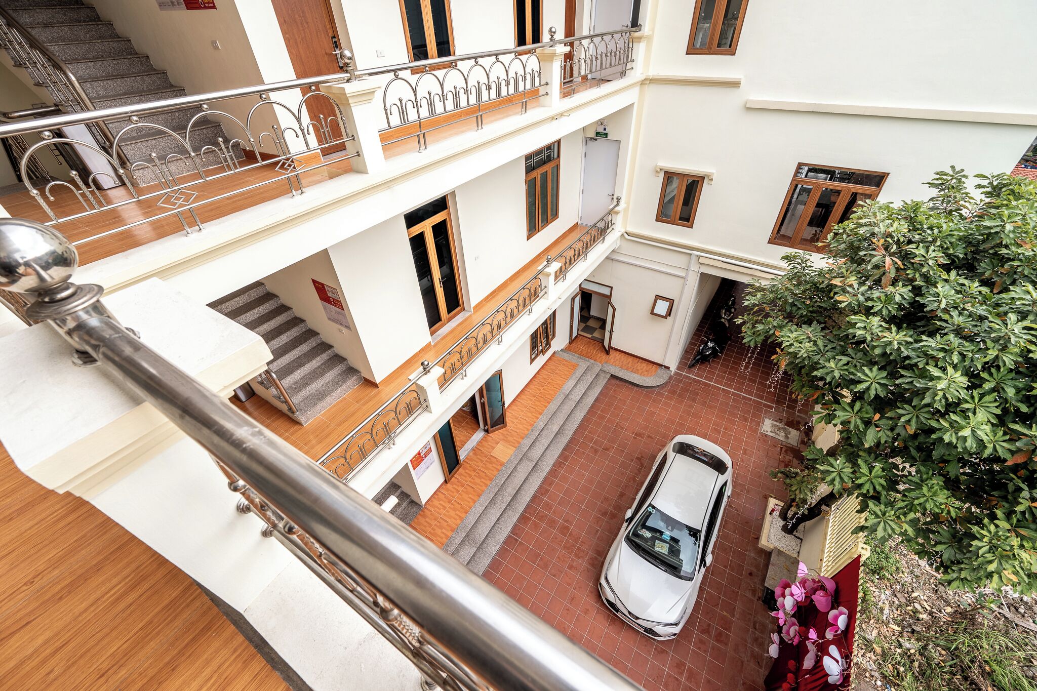 Un edificio a più piani con un'auto parcheggiata al piano terra, una scala e un balcone con ringhiere in metallo.