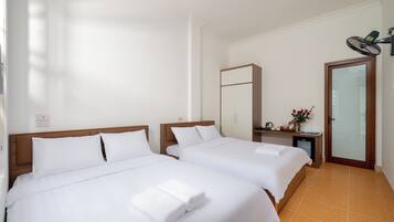 Une chambre d’hôtel avec deux lits, un petit bureau avec une chaise, un miroir et une porte avec un panneau de verre.