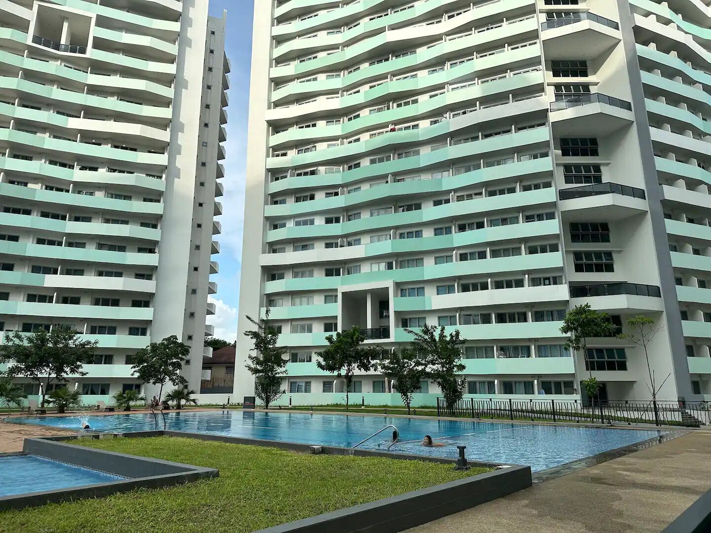 A high-rise residential building with multiple balconies and a swimming pool area.
