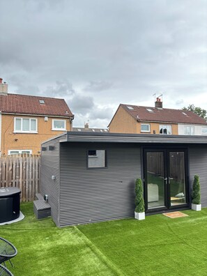 A modern outdoor patio area with a built-in seating area, a small shed, and a well-maintained lawn. - Charming house with sauna in Glasgow perfect for your getaway (Glasgow)