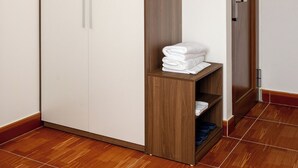 Ein Schrank mit Holzpaneelen, ein Ablagefach mit gefalteten Handtüchern und eine Tür mit Griff.