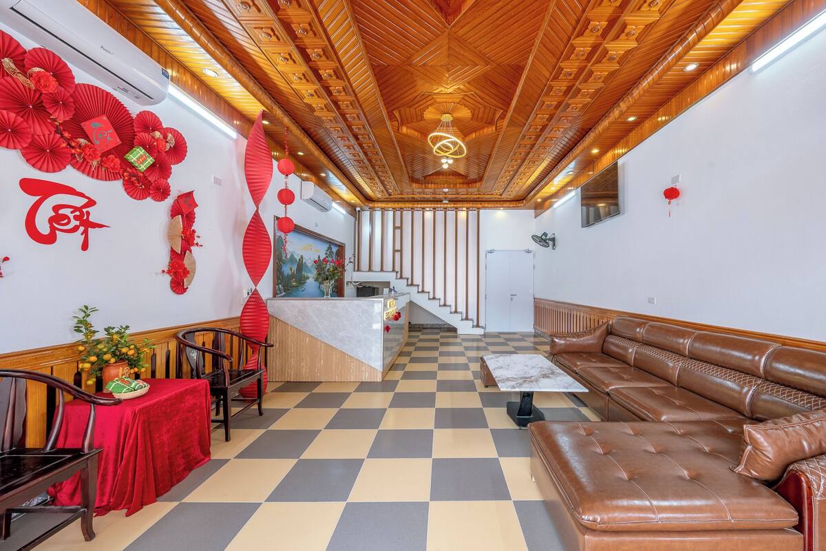 A hotel lobby with a checkered floor, a reception desk, a sofa, and a staircase.