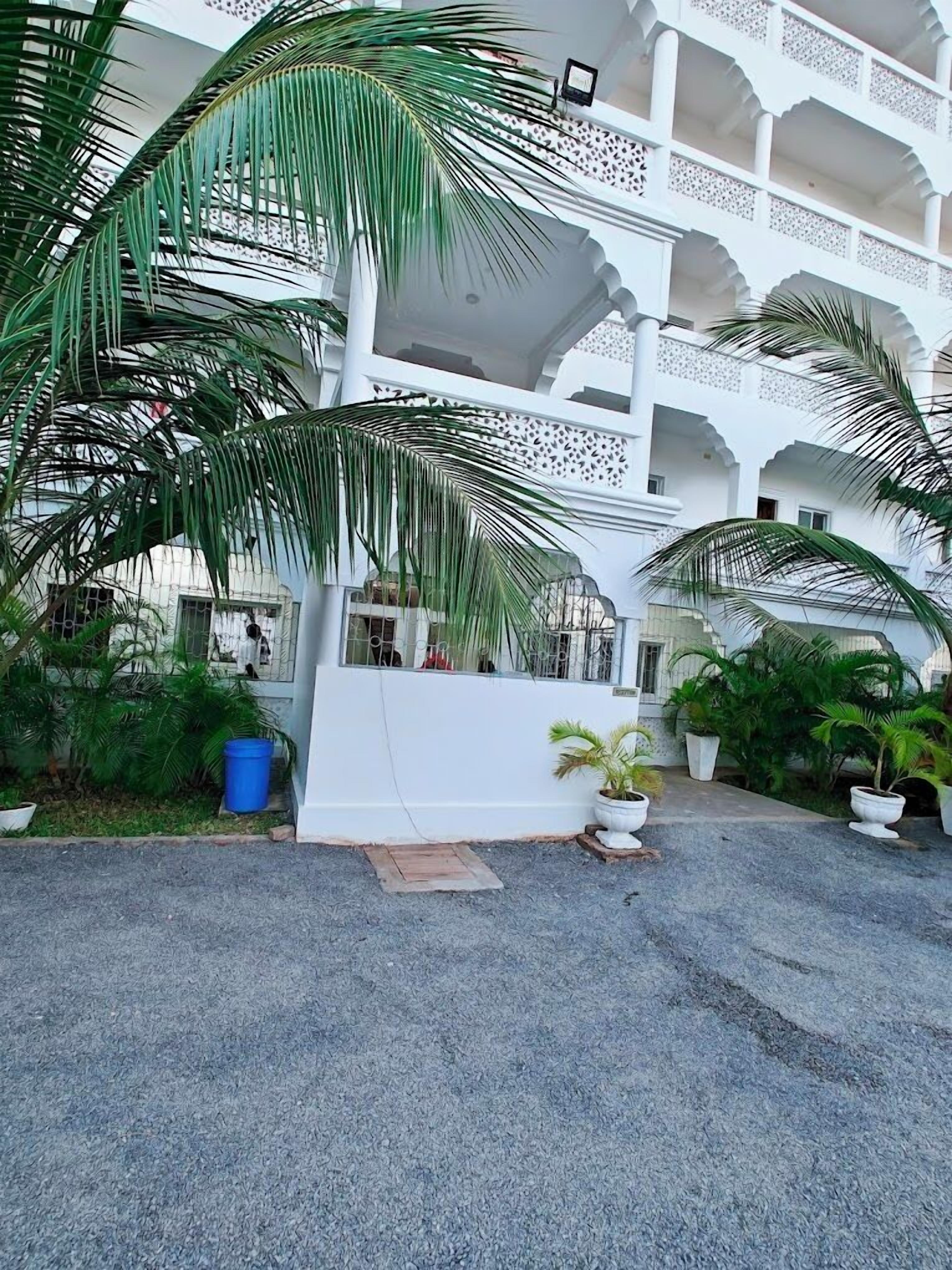 A multi-story building with a white exterior and traditional architectural design, featuring balconies and a covered walkway.