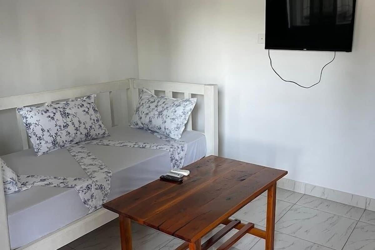 A room with a white sofa, a wooden table, and a wall-mounted TV.