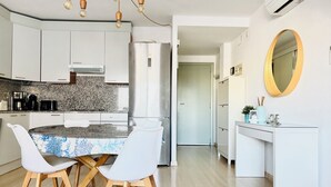 Una cocina moderna con armarios blancos, encimera de granito y comedor con sillas blancas y una mesa de madera.