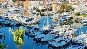 Un puerto deportivo con varias embarcaciones amarradas, rodeado de edificios residenciales con tejados de tejas rojas.