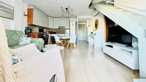 Un apartamento moderno con sala de estar, comedor, cocina y una escalera que conduce a un nivel superior.
