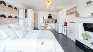 Un dormitori modern i ben il·luminat, amb un llit gran, una zona de dinar petita i un petit espai cuina.