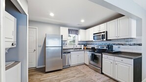 Una cocina moderna con armarios blancos, electrodomésticos de acero inoxidable y suelo de madera.