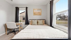 Un dormitorio con cama, escritorio y ventana.