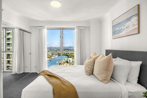 A hotel room with a large bed, a view of a marina, and a balcony with a cityscape. - Chevron Renaissance Ocean & River Views (Surfers Paradise)