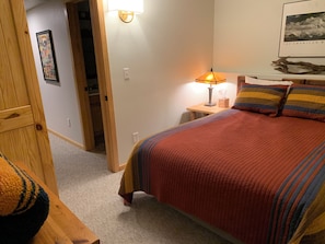 Une chambre à coucher avec un lit, une table de chevet, une lampe et un tableau encadré au mur.