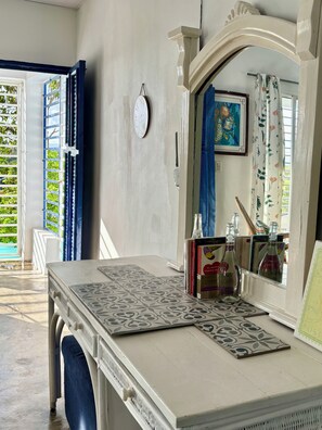A room with a bed, a table with a book and bottles, a window with blue curtains, and a wall-mounted clock. - Terrific 2-bedroom house with AC in sunny Higüey (Higüey)