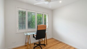 A room with a desk, chair, and large windows with blinds. - The Glenlorne: Your Serene Retreat Awaits (Kiama)