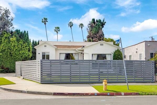 A modern house with a white exterior, a grey fence, and a fire hydrant in front. - Stunning Luxurious Home, near Beverly Hills & DTLA (Los Angeles)