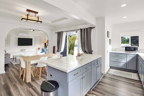 A modern kitchen with a central island, grey cabinets, and a microwave. - Stunning Luxurious Home, near Beverly Hills & DTLA (Los Angeles)