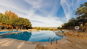 En swimmingpool med en stenbelagd poolkant, omgiven av träd och en klar himmel.