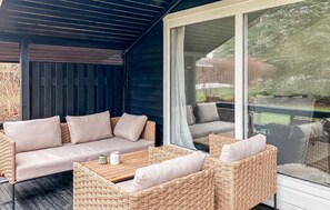 A covered outdoor seating area with wicker furniture and a glass door leading to a garden. - 2 bedroom nice home in Hundested (Hundested)