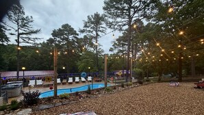 A pool area with lounge chairs, a covered seating area, and string lights. - Resort Pool, Hot Tub, Firepit & Cornhole (Branson)