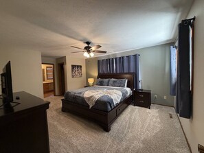 A bedroom with a bed, bedside tables, a ceiling fan, and a view of a hallway. - Resort Pool, Hot Tub, Firepit & Cornhole (Branson)