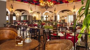 Un restaurant doté de nombreuses tables et chaises, d’un lustre et d’un plafond aux couleurs vives.