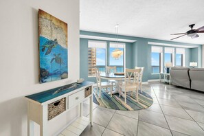 Ein geräumiges Wohnzimmer mit Essbereich, großen Fenstern, Deckenventilator und Meerblick.