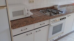 Una cocina con estufa a gas, horno, microondas y campana extractora integrada.