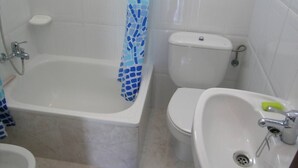 A bathroom with a bathtub, toilet, and sink. - Ignacio C at the beach in Lariño (Lariño)