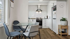 Una cocina compacta con armarios blancos, una estufa de acero inoxidable y un diseño moderno.