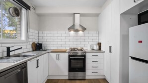Una cocina moderna con armarios blancos, una estufa de acero inoxidable y un horno empotrado.