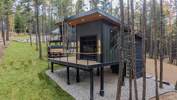 Une cabane dotée d’une terrasse, entourée d’arbres.