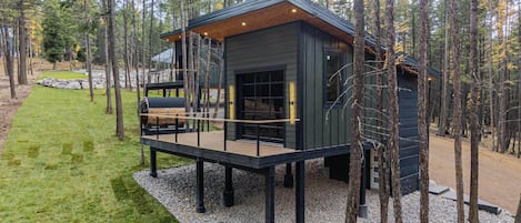 A cabin with a deck, surrounded by trees.