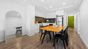Una cucina moderna con mobili bianchi, un tavolo da pranzo in legno e sedie nere.