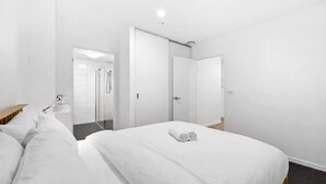 Una camera d'albergo con un letto, una scrivania, una sedia, una lampada e un angolo doccia.