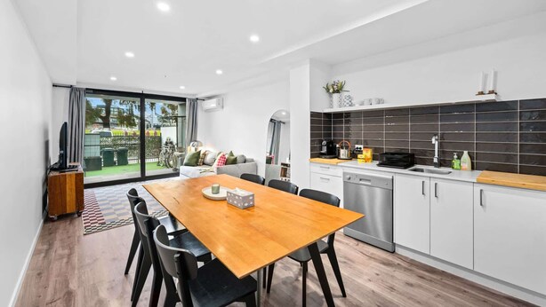 Una cucina moderna con zona pranzo, caratterizzata da un tavolo grande e sedie, lavastoviglie e vista sull'esterno.