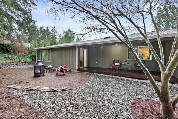 Een modern huis met een overdekte patio, een pad van natuursteen en buitenmeubilair.