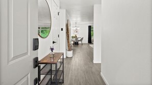 A hallway with a wooden table, a potted plant, and a door with a security device.