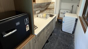 Ett kompakt kök med ett inbyggt kylskåp, en diskho och en kombinerad tvätt- och torkmaskin.
