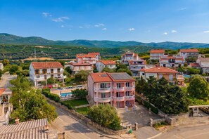 A residential area with multi-story houses, a swimming pool, and a mountainous backdrop. - Pool Apt 2 - Novi Vinodolski (Sea View), Novi Vinodolski, Croatia (Novi Vinodolski)