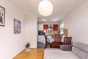 A modern living room with a sofa, a dining table set for two, and a kitchen in the background. - Pool Apt 2 - Novi Vinodolski (Sea View), Novi Vinodolski, Croatia (Novi Vinodolski)