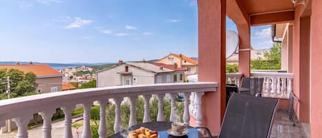 A balcony with a table set for two, a cup of coffee, and a plate of pastries.