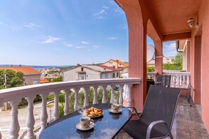 Ein Balkon mit einem Tisch für zwei Personen, einer Kaffeetasse und einem Tablett Gebäck.