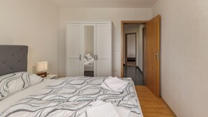 Ein Schlafzimmer mit Bett, Nachttisch, Kleiderschrank und einer Tür zu einem anderen Raum.