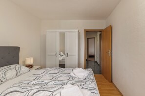 Ein Schlafzimmer mit Bett, Nachttisch, Kleiderschrank und einer Tür zu einem anderen Raum.