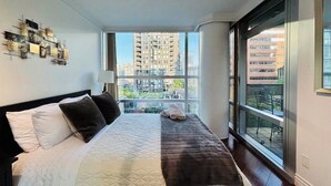 Una camera da letto con un letto grande, vista sulla città attraverso una finestra e un elemento decorativo a parete.