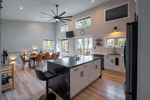 A modern kitchen with a large island, white cabinetry, and a dining area with a table and chairs.