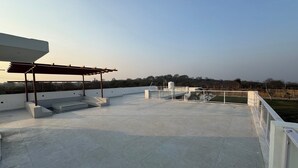 Una terraza en la azotea con una pérgola, zonas de estar y vistas del paisaje circundante.